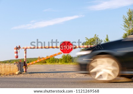 The barrier at the entrance to the forest and the car in motion.