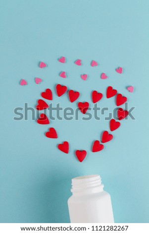 Image of heart made up out of red tablets on the blue background