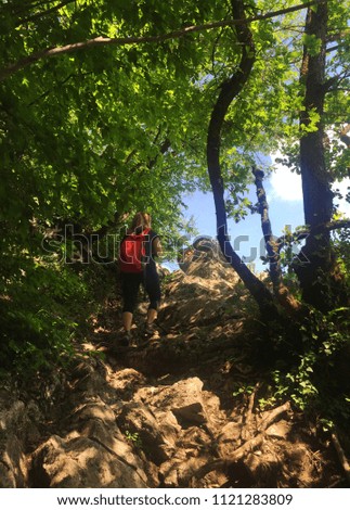 Girl hiking in mountains through forest path wearing mountain boots, nature background