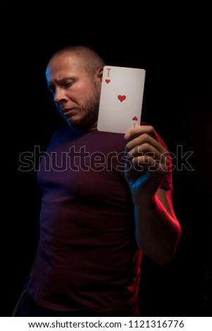 A man holds a deck of cards and shows tricks in a scenic light. The photographer is the author of the design of playing cards, which is written in the release of the property.