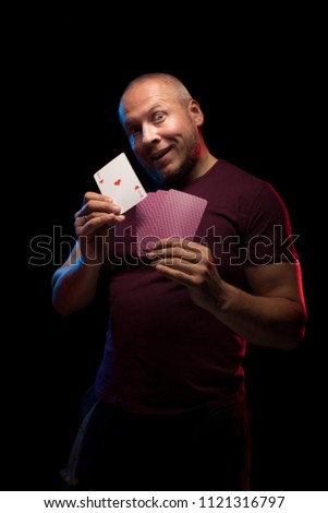 A man holds a deck of cards and shows tricks in a scenic light. The photographer is the author of the design of playing cards, which is written in the release of the property.