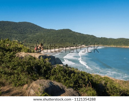 Young photographer takes picture from the top of the hill on Naufragados beach, in Florianopolis, Brazil.