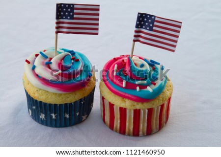 Happy 4th of July conceptual image with patriotic multicolored icing cupcakes and American flags.