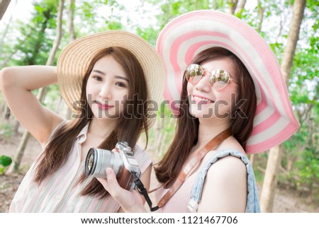 two beauty woman take camera and go travel happily in the forest