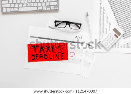 Taxes deadline words on office work desk with calendar and bills on white background top view copy space. Circled dates