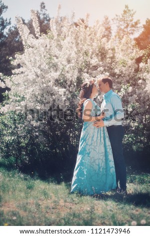 Man hugs his pregnant woman from behind standing in the forest