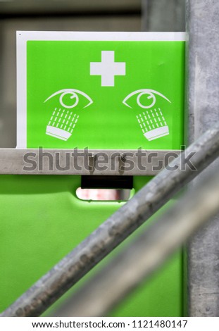 A high visability lime green safety sign for locating a eye wash station in an industrial facility.