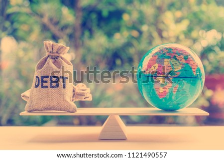 World or global / national debt crisis or imbalance concept : Debt bag, world globe on a balance scale, depicts the government's fiscal profligacy, excessive expenditure or increase public spending. Royalty-Free Stock Photo #1121490557