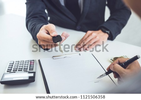Salesman send key to customer after man signing car document contract good deal agreement, successful car loan contract buying or selling new vehicle.