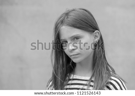 Beautiful blond young girl with freckles outdoors on wall background, close up portrait, black and white