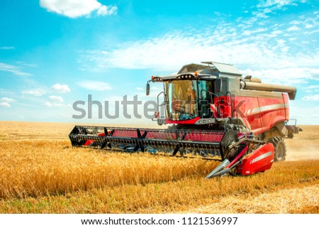 harvester harvests wheat on the field Royalty-Free Stock Photo #1121536997
