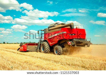 harvester harvests wheat on the field Royalty-Free Stock Photo #1121537003