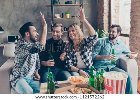 Give me five! Attractive, successful guys clapping palms, congratulate each other, their friends looking and laughing at them, four persons sitting in livingroom together, having eating snacks
