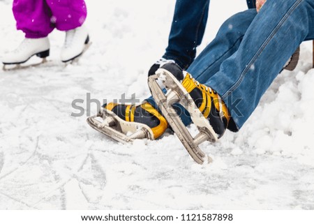 Rest after skiing. A man in yellow skates sits on a natural ice rink in the open air
