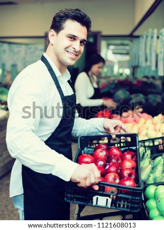 Market workers with assortment of sweet apples, prices on Spanish