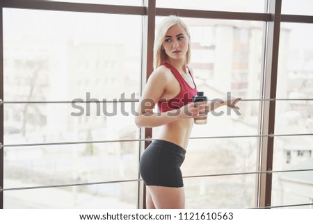 Photo of attractive fitness woman in gym holding bottle of water.