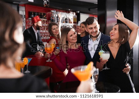 Cheerful guy with two girls partying in bar, dancing and toasting drinks