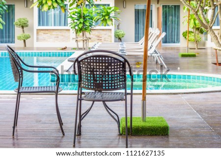 Modern table and chairs on wooden decks at the side of swimming pool. For relaxation and recreation in hotel resort.