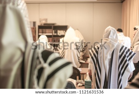 Backside view of congregants in a Jewish synagogue wrapped in prayer shawls during prayer Royalty-Free Stock Photo #1121631536