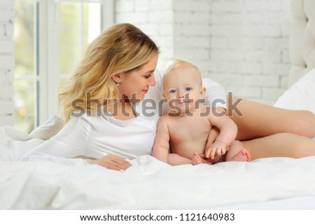 Family portrait of mother and child in white clothes in bed.
