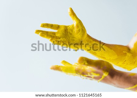 Cropped view of male hands covered with yellow paint isolated on white background