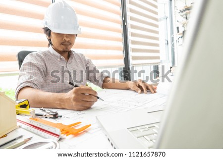 Engineering man working on blueprint plan with architect tools beside. Selective focus. 