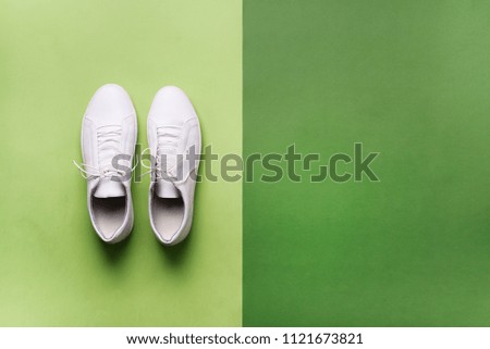 Stylish white sneakers and rope on green background with copy space. Top view. Minimal flat lay. Summer shoes collection. First step concept.