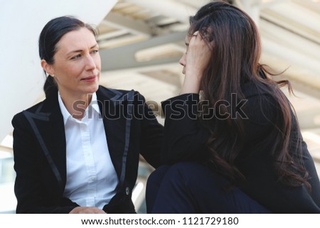 Businesswoman consoling her friend that suffering from headache about problem working, female is frustrated about work and friend's hand on shoulder of colleagueat outside building  Royalty-Free Stock Photo #1121729180