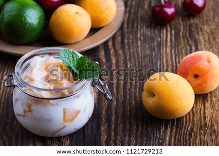 Healthy breakfast with apricot yogurt and fresh summer fruits, sweet cherry, lime and strawberry on rural table