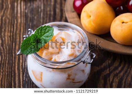 Healthy breakfast with apricot yogurt and fresh summer fruits, sweet cherry, lime and strawberry on rural table