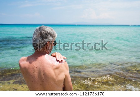 Senior man using sun protection cream on summer vacation
