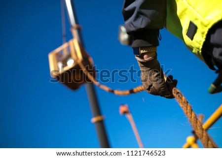 Rope access rigger worker commencing high risk job wearing heavy duty glove holding a safety tag line rope to control load swing while crane is lifting in construction building site, Perth Australia 
 Royalty-Free Stock Photo #1121746523