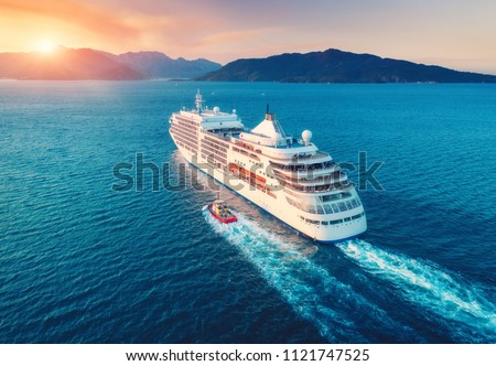 Cruise ship at harbor. Aerial view of beautiful large white ship at sunset. Colorful landscape with boats in marina bay, sea, colorful sky. Top view from drone of yacht. Luxury cruise. Floating liner Royalty-Free Stock Photo #1121747525