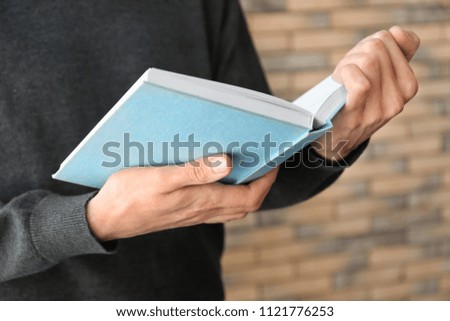 Man reading interesting book at home, closeup