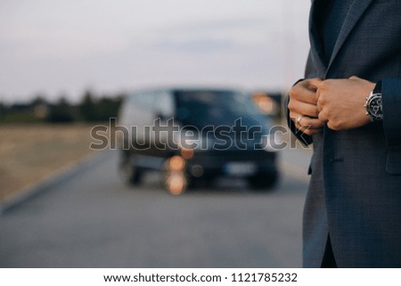 Man in suit in front of luxury car minivan at the background. Driver of the car is waiting for passenger  Royalty-Free Stock Photo #1121785232