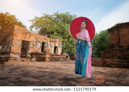 Thai girl holding a red umbrella. Beauty fantasy Thai woman. Beautiful Thai girl in traditional dress costume, Ayutthaya province, Thailand.