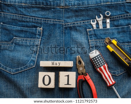wooden block calendar 1 May and Joinery tools on a jean texture background. Labor day concept.