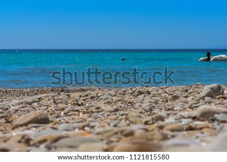 low view on stone beach ans clear blue adriatic sea against blue sky in croatia