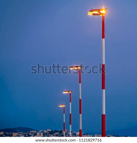 Row of the airport lamp posts with alternate red and white painting on blue sky background