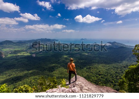 man standing on rock at sunset with mountains below