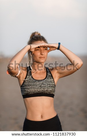 Beautiful Caucasian sportswoman standing outdoors and looking at the sun.