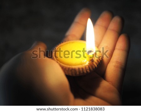 Burning tea candle is on the hand in the night.