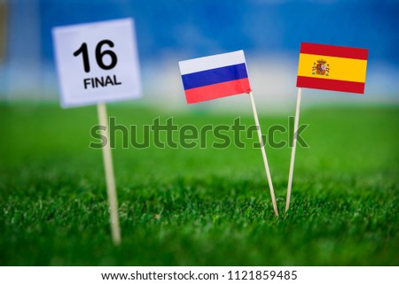 Russia and Spain national Flag on green grass. White table with tittle “16 FINAL”