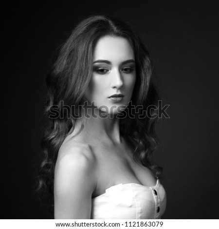 Classical portrait of young beautiful woman with long brown hair psing against brown background. Studio shot of calm pensive thoughtful girl not looking in camera