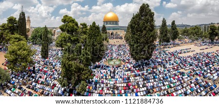 landscape of muslim people doing Friday prayer in Al-aqsa mosque yards with trees surrounding them and the golden Dome of the rock in the middle with a blue sky at Jerusalem Royalty-Free Stock Photo #1121884736