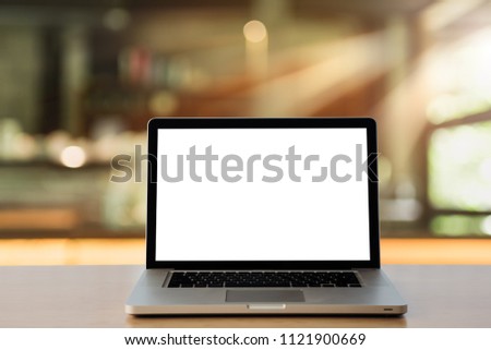 Workspace wood desk with Laptop with blank screen,Interior cafe blurred background at light bokeh.