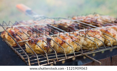 Marinated chicken legs on the grill in the smoke. A picnic, tasty food. BBQ.