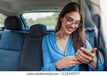 Beautiful business woman in car. Woman using smartphone in the car. Woman talking on cellphone while traveling in the car. Internet and social media