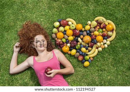 Girl with fruit lying on the grass