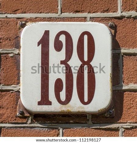 enameled house number one hundred and thirty-eight. Brown lettering on a white background.